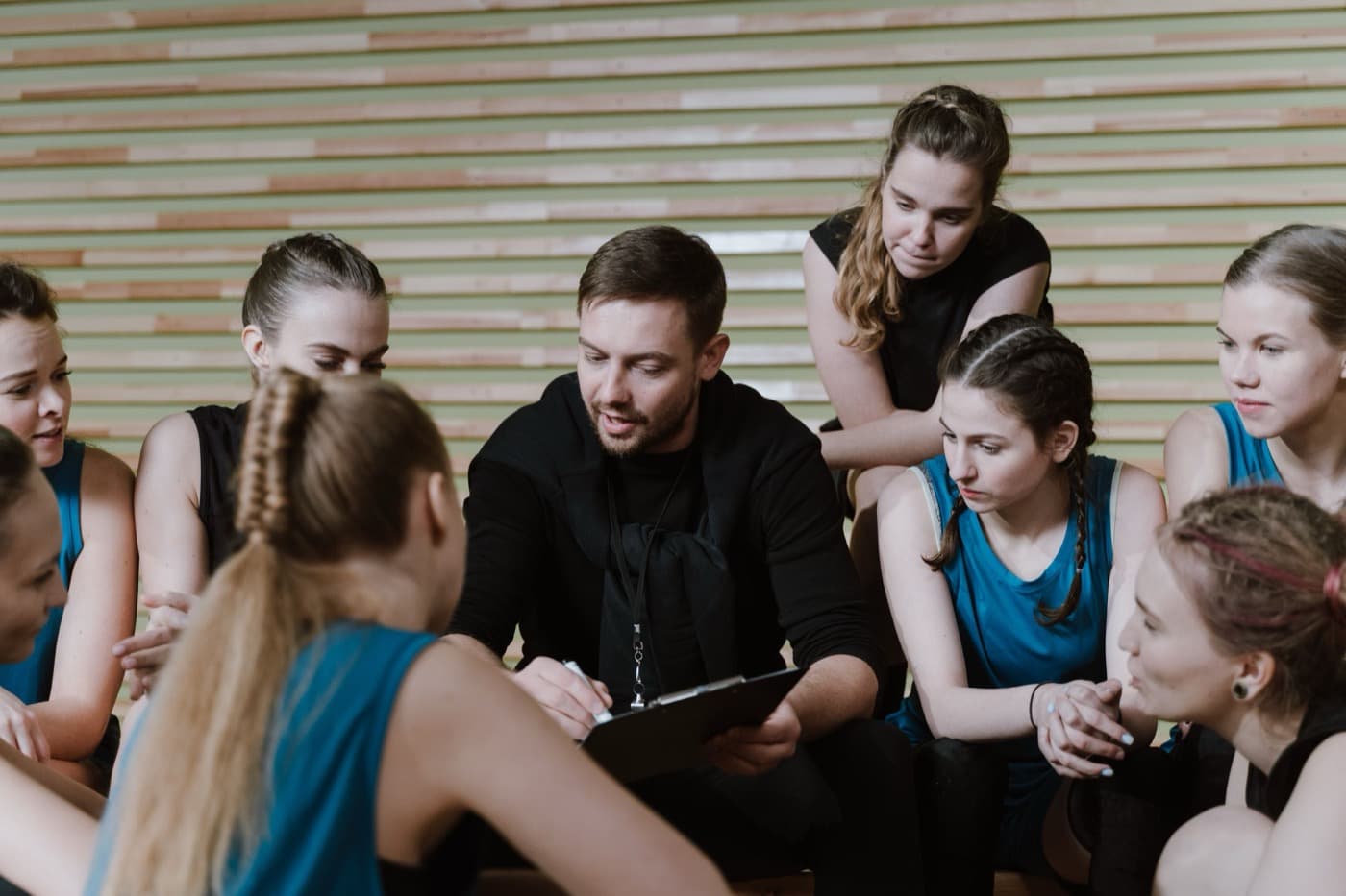 Coach expliquant la stratégie à son équipe de volley réunie autour d'elle