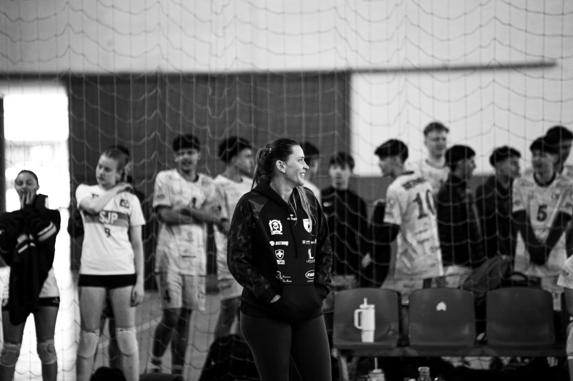 Coach souriante entourée de son équipe de volley en salle